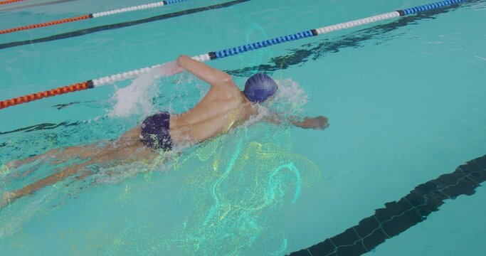 Gliding adult swimmer in pool lane pulling arm back between dividers, wearing blue cap and trunks
