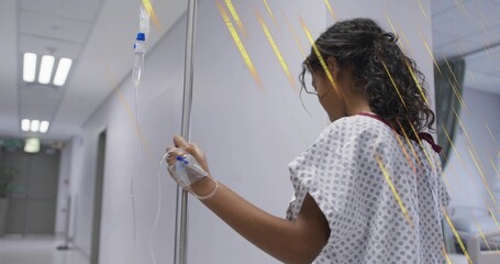Walking child patient gripping IV pole wearing gown in hospital corridor with IV bag, copy space