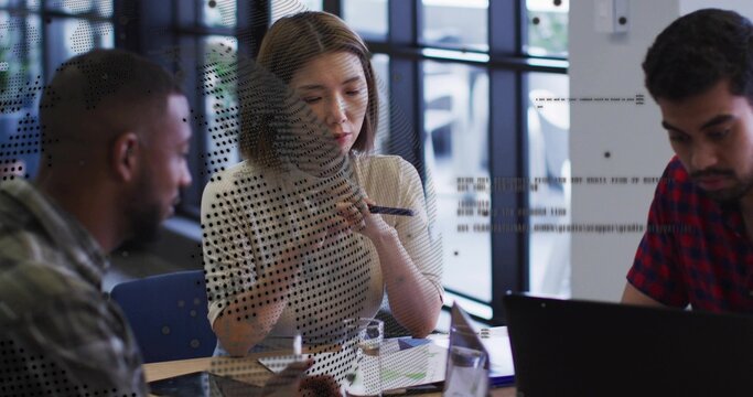 Collaborating three professionals reviewing charts in conference room, with laptop and tablet