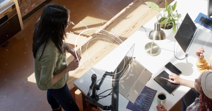 Collaborating software developers analyzing code and data charts in office, with laptops, monitors