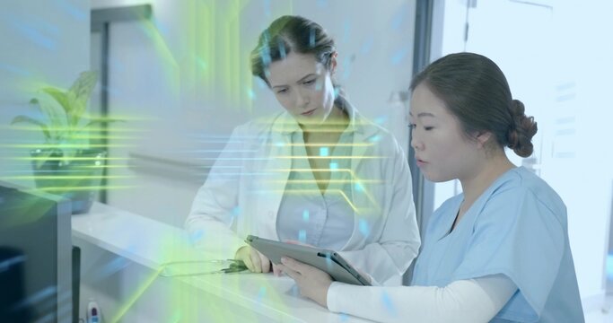 Medical team wearing scrubs and coat reviewing records on tablet in reception with digital overlay