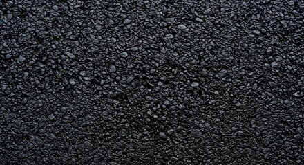 Close-up abstract texture of dark grey granular asphalt paving, revealing tiny pebbles and aggregate within the road surface material construction backdrop