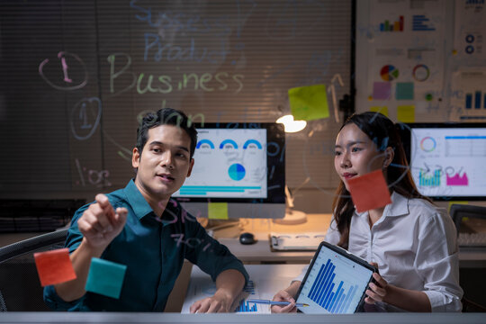 Business colleagues brainstorming data analysis late in office - Powered by Adobe