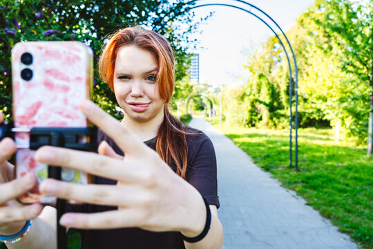 Young person vlogging with smartphone in sunny park showing creative expression