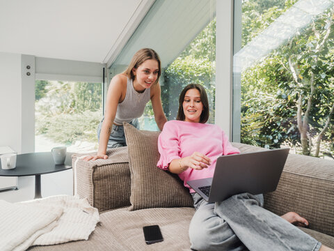 Sisters planning together on laptop in modern living room