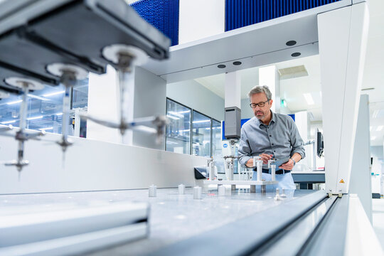 Engineer using tablet and operating measurement machinery in factory