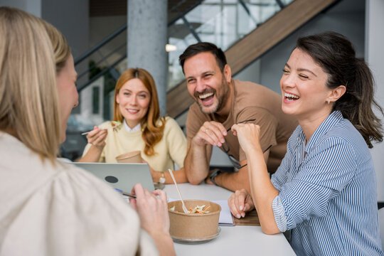 Young dynamic team laughing together during casual office lunch