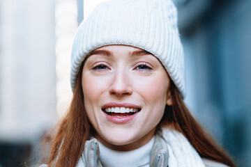 Smiling woman enjoying a winter day in the city with warm clothing and a cozy beanie