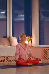 Two women meditate together in a peaceful evening yoga studio, focusing on mindfulness, breathing, and harmony.
