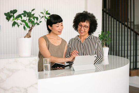 Team working and explaining at hotel reception desk with tablet