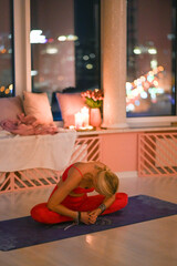 Yoga instructor communicates with her student, discussing breathing and posture in a cozy studio environment filled with soft candlelight.
