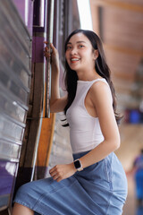 Young asian woman smiling boarding a train