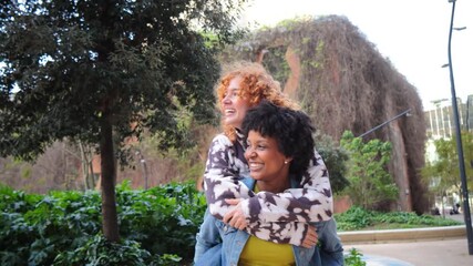 Two joyful women are sharing a delightful moment as one gives the other a piggyback ride filled with laughter and happiness, showcasing their strong bond and friendship in a playful manner.