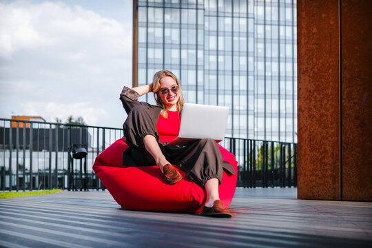 Woman enjoying remote work and flexibility outdoors on bean bag