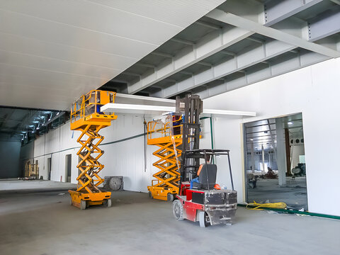Construction site interior with scissor lifts and forklift during building work