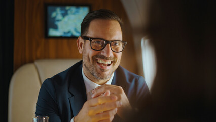 Business executive laughing and making a point during a meeting inside a luxurious private jet, symbolizing success, wealth, and efficient corporate travel
