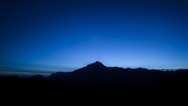 A majestic mountain silhouette against a twilight sky, radiating calm and natural beauty.