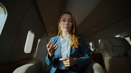 Businesswoman having a video call on a private jet, discussing business while traveling, symbolizing remote work, success, luxury, and exclusive executive travel