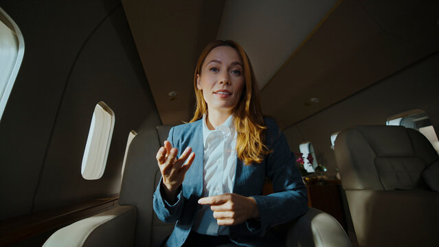 Businesswoman having a video call on a private jet, discussing business while traveling, symbolizing remote work, success, luxury, and exclusive executive travel