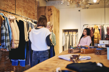 Fashion consultant helping customer choose clothes inside boutique store