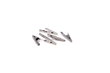 Small stainless alligator clips arranged on white backdrop for electronics