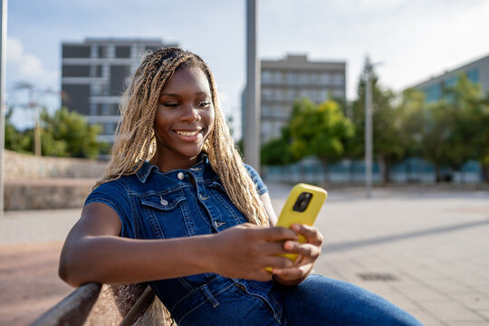Young african american woman smiling using smartphone outdoors