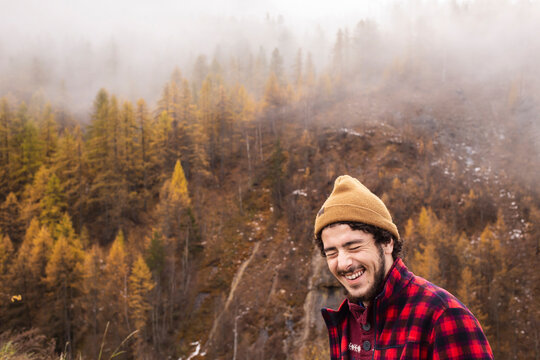 Happy young man standing on mountain in foggy weather