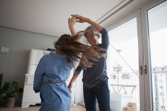 Little girl dancing with her grandmother at home