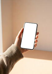Female hand holds contemporary smartphone with blank white screen, perfect for app mockups and copy space