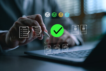 Businessman using stylus to check digital documents on laptop with green check mark icon,...