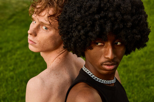 Young gay couple with curly hair in front of grass