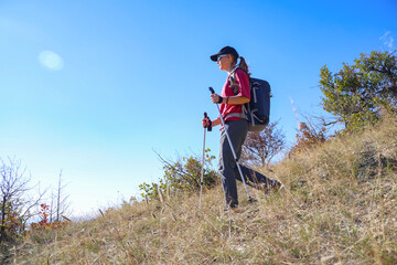 young girl with a backpack is hiking alone in nature
