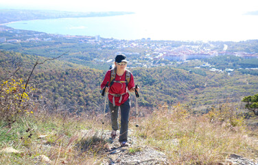 young girl with a backpack is hiking alone in nature