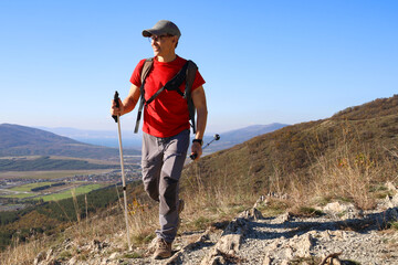 young manl with a backpack is hiking alone in nature