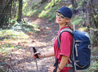 young girl with a backpack is hiking alone in nature