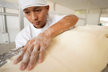 Fototapeta premium Asian man drying handmade noodles outdoors at a traditional noodle factory. Local food production process representing culture, craftsmanship, and dedication in authentic Asian cuisine.