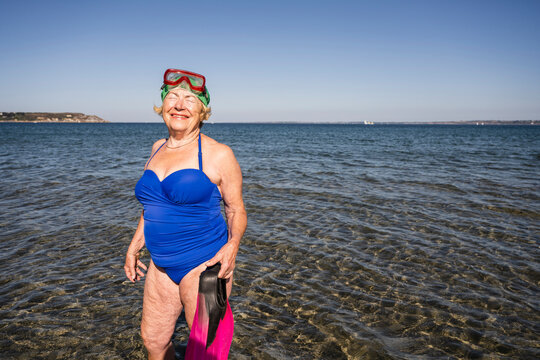 Smiling woman with diving flippers standing in sea