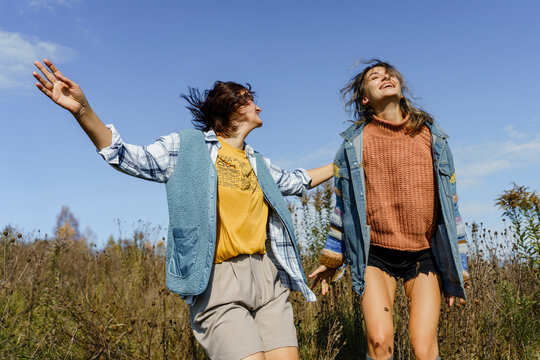 Friends dancing and enjoying carefree time outdoors in a field