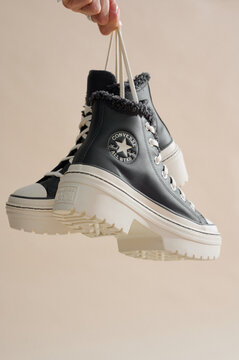 2025-11-03, Minsk, Belarus, fashionable black converse sneakers with high-top design held in hand highlighting casual style