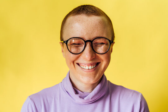Happy woman with eyes closed against yellow background