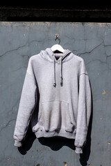 Stylish Gray Hoodie Hanging Casually Against Textured Wall Ideal for Fashion Blogs