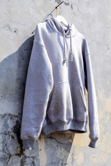 Stylish Gray Hoodie Hanging Against Textured Concrete Wall