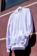 Stylish White Hoodie Mockup on Hanger Against Vibrant Wall Ready for Your Design Perfect for Fashion