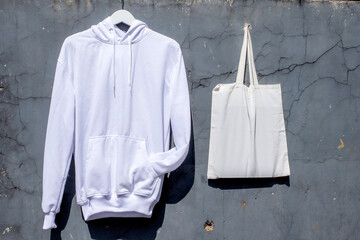 Showcase Your Brand With Pristine White Hoodie and Tote Bag Against Textured Wall
