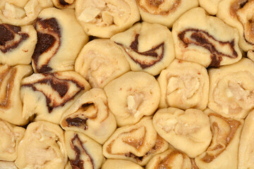 A close-up, full-frame shot of unbaked yeast dough spirals filled with melted chocolate and hazelnut paste, showing the interior swirls