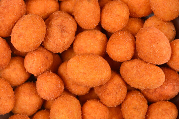 An extreme close-up, full frame shot of numerous orange, coated peanuts, showcasing their crunchy, textured surface