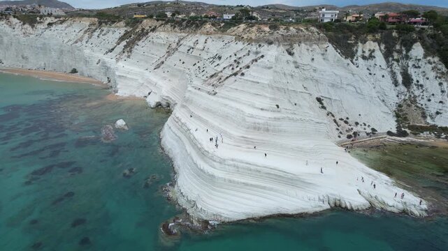 Aerial drone footage of Scala dei Turchi, Sicily: white marl cliffs descending into turquoise sea, coastal waves and dramatic Mediterranean light. Ideal for travel, nature, and heritage projects.