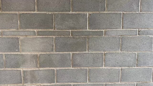 Close up shot of a concrete brick wall. Gray concrete block wall. Industrial backdrop in a construction site.
