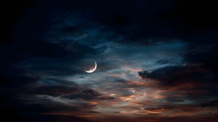 A luminous crescent moon hangs in a dramatic twilight sky filled with moody clouds and subtle hues