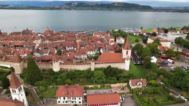 4K cinematic drone view of Murten medieval town, castle and lake. Aerial panorama of historic fortress walls and traditional Swiss architecture. Canton Fribourg, Switzerland.